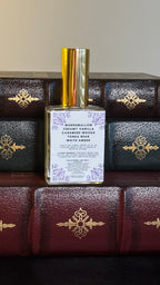 Back label of Maison of Stories Fated Mates body oil 50ml with rococo floral corner details and marshmallow, creamy vanilla, cashmere woods, tonka bean and white amber scent notes, displayed on vintage leather-bound books