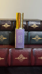 Maison of Stories Fated Mates body oil 50ml spine view with lavender label showing scent name, displayed on vintage leather-bound books