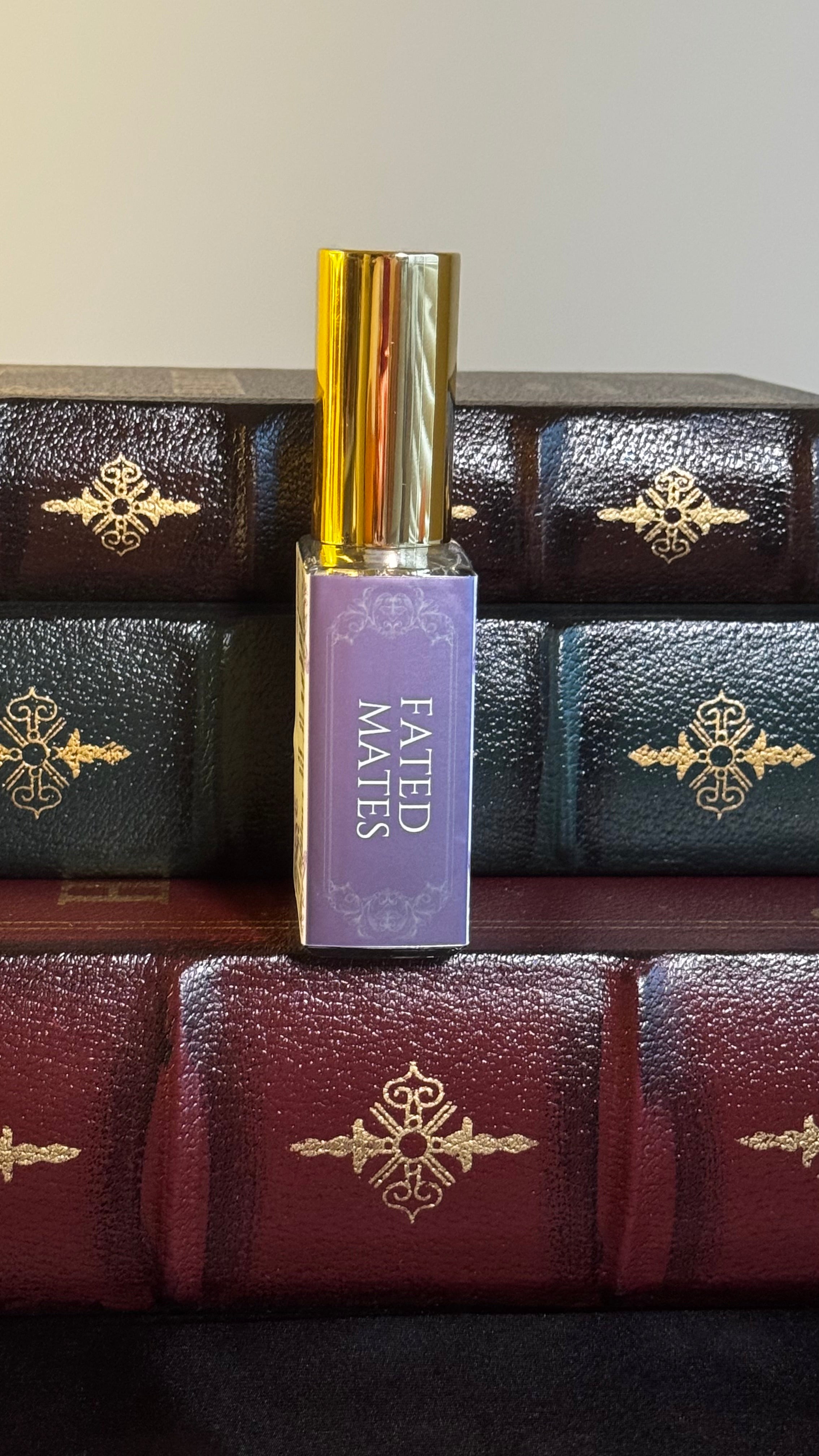 Maison of Stories Fated Mates body oil 50ml spine view with lavender label showing scent name, displayed on vintage leather-bound books