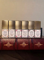 Maison of Stories First Editions Collection six body oil 15ml bottles back label view showing scent notes and rococo floral details on vintage leather-bound books