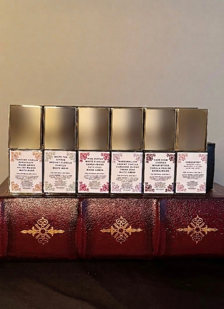 Maison of Stories First Editions Collection six body oil 15ml bottles back label view showing scent notes and rococo floral details on vintage leather-bound books
