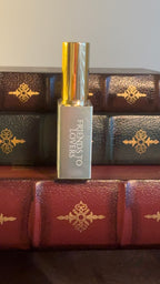 Maison of Stories Friends to Lovers body oil 50ml spine view with sage green label showing scent name, displayed on vintage leather-bound books